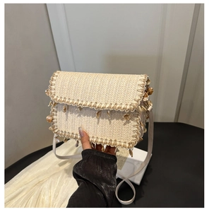 Detail of woven straw bag with real seashell accents and white fringe tassels