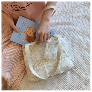 Close-up of white floral lace tote bag with cream synthetic leather handles for summer