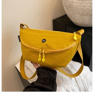 Detail of bright yellow crossbody bag with circular OK logo and fashion label