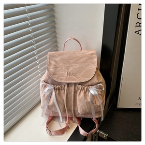 Détail du sac à dos rose à nœud avec tissu texturé plissé et broderie Nika