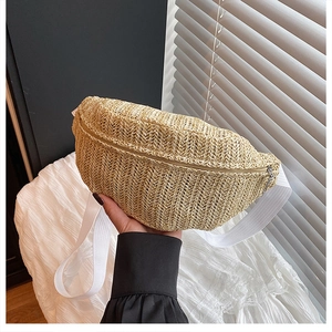 Detail of woven straw chest bag featuring beige natural texture and white textile strap