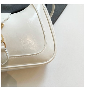 Dettaglio borsa bianca in pelle con trama litchi e anello in metallo dorato lucido