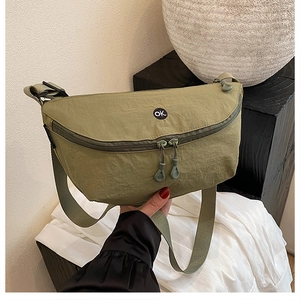 Detail of the green nylon crossbody bag showing the OK logo and wrinkled texture