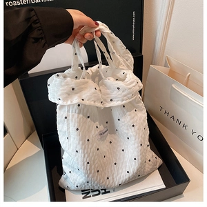 Detail of white pleated tote bag featuring small black flowers and Fashion Bag label