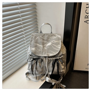 Détail du sac à dos argenté plissé avec broderie Nika et nœuds en satin noir