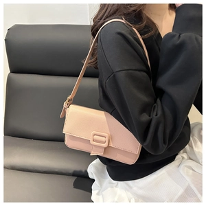 Detailed texture of pink litchi grain leather shoulder bag worn by model on sofa