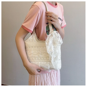 Detail of cream lace tote bag with layered floral ruffles and a large ribbon bow