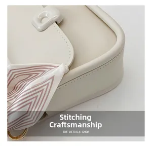 Close-up of minimalist beige leather handbag with precision stitching and scarf detail