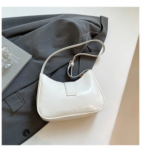 Vista dall'alto di una borsa a mezzaluna bianca lucida con design minimalista su rivista