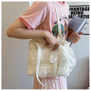 Detailed close-up of cream lace tote bag featuring elegant ruffles and a large mesh bow