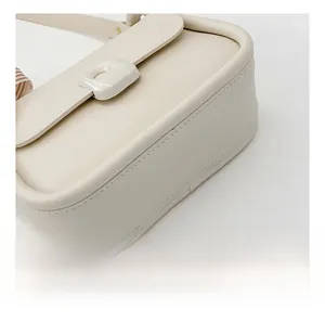 Detail of cream flap crossbody bag with unique metal clasp and striped silk scarf wrap
