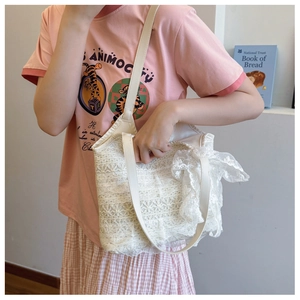 Detailed view of white lace tote bag with floral mesh layers and side ribbon bow
