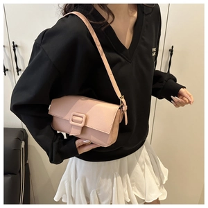 Detail of pink lychee grain leather shoulder bag worn by model in minimalist indoor setting
