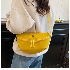 Detail of a bright yellow nylon crossbody bag featuring an OK embroidery and zipper closure