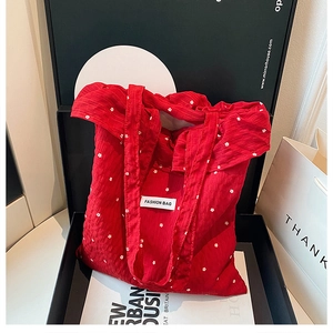 Detail of red floral canvas tote bag with fashion label inside a premium gift box