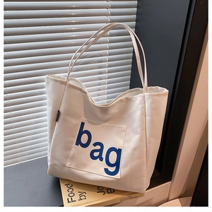Close-up of a white canvas tote bag detail featuring a blue bag print and a side pocket