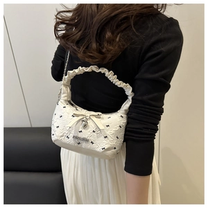 Detail of floral jacquard texture with black bows and heart pendant on white bag