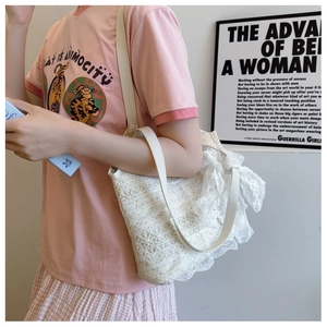 Close-up of white lace shoulder bag featuring floral embroidery and bow details