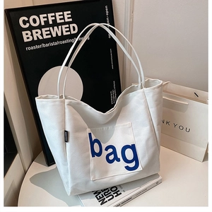 Detailed close-up of white canvas tote bag featuring a blue bag letter print on front