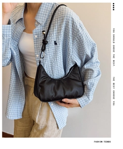 Detail of a black hobo shoulder bag with a unique metal ball knot on a minimalist strap