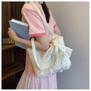 Detail of floral lace tote bag featuring elegant bow decor and white faux leather straps