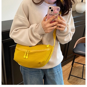 Detail view of bright yellow crescent bag showing matte texture and dual zipper pulls