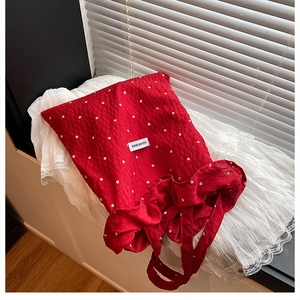 Detail of red floral fabric tote bag featuring white flower pattern and fashion bag label