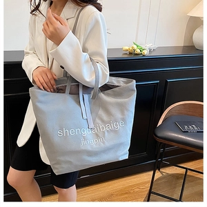 Detail of grey canvas tote bag with embroidered letters and spacious internal storage