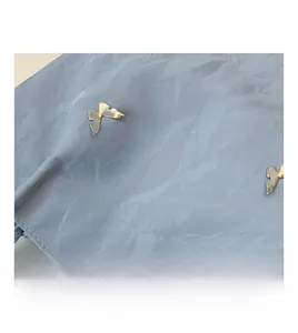 Close-up of light blue marble texture fabric with silver metal butterfly ornament