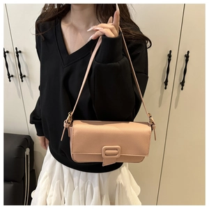 Close-up of pink baguette bag with lychee texture and buckle detail on a female model