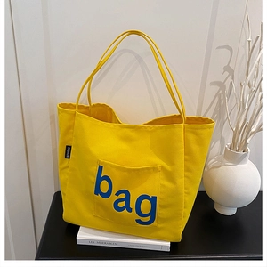 Detail of yellow canvas tote bag with blue letter pocket and long shoulder straps