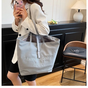 Détail du grand sac cabas en toile gris clair avec broderie porté à l'épaule pour les cours