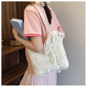 Detailed side view of a white lace tote bag with a large bow on a wooden shelf