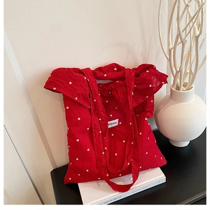 Detail of red floral canvas tote bag with ruffled edges on a minimal desk setup