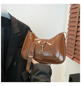 Dettaglio borsa a spalla in vernice marrone scuro con fibbia a pistone in metallo dorato