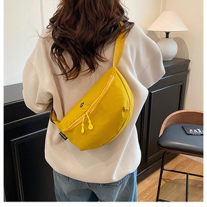 Detail view of a yellow nylon sports crossbody bag worn on back with FASHION label