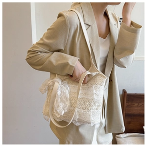 Detail of cream lace tote bag featuring delicate floral lace layers and side ribbon bow