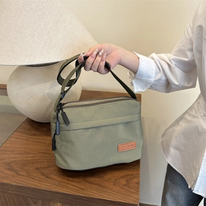 Sac bandoulière en nylon vert imperméable avec plusieurs compartiments et sangle réglable