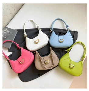Flat lay of colorful crescent-shaped suede handbags with gold D-buckles and knotted handles