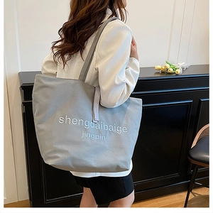 Détail du grand sac cabas en toile grise avec broderie blanche et bandoulière large