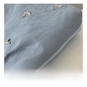 Detail of light blue wrinkled fabric with decorative silver metal butterfly buckles