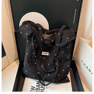 Detail of floral black tote bag in gift box with fashion bag label and textured fabric