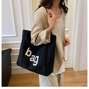 Detailed shot of large black canvas tote bag with bag text print and fashion woven label