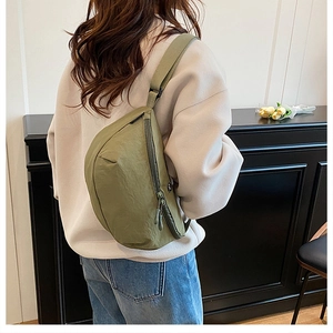 Olive green nylon crescent bag detail showing wide strap and zipper on casual model