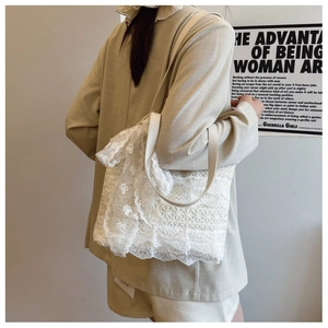Close-up of white lace tote bag with floral embroidery and cream leather handles