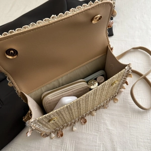 Handmade straw shoulder bag with tassels and shell charms showing interior capacity