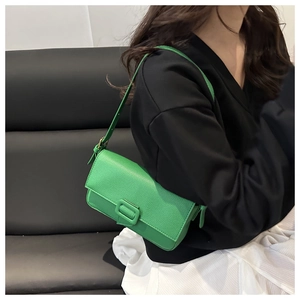 Close-up of green baguette bag in lychee pattern leather with stylish buckle and strap