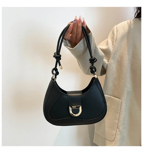 Detail of black faux leather half-moon bag with gold D-buckle and knotted shoulder strap
