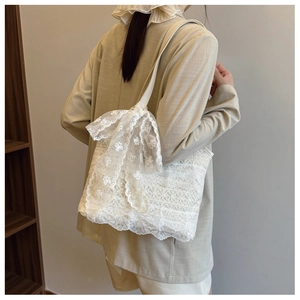 Detailed view of floral lace pattern and decorative bow on white crochet tote bag