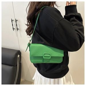Detail of vibrant green baguette bag showing textured lychee leather and square buckle
